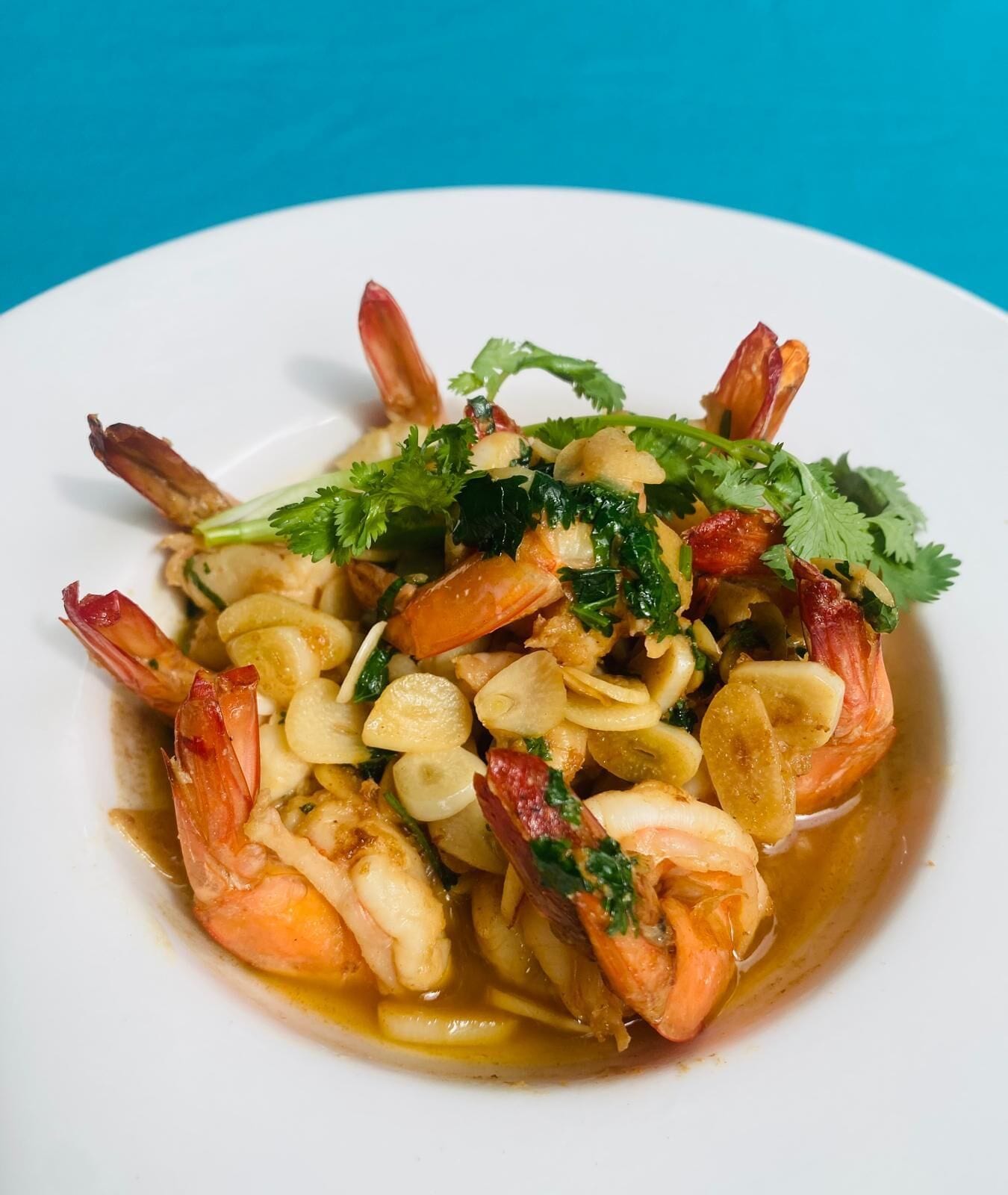 A plate of shrimp with vegetables and herbs.