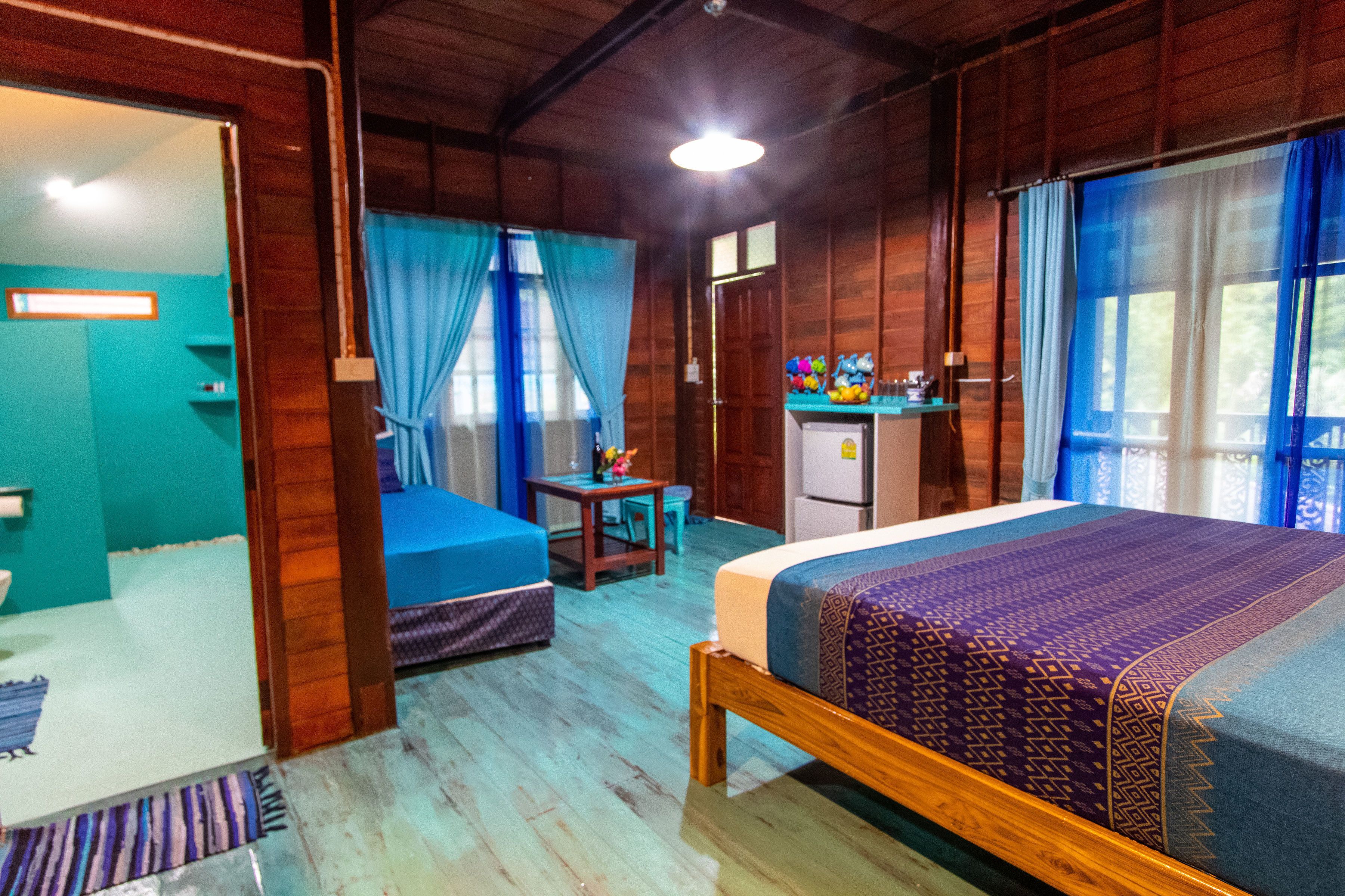 A wooden cabin with a bed, a desk, and a kitchenette.