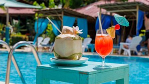A poolside table with a coconut drink and a tropical cocktail. - Baan Kiao Resort (Ko Pha-ngan)