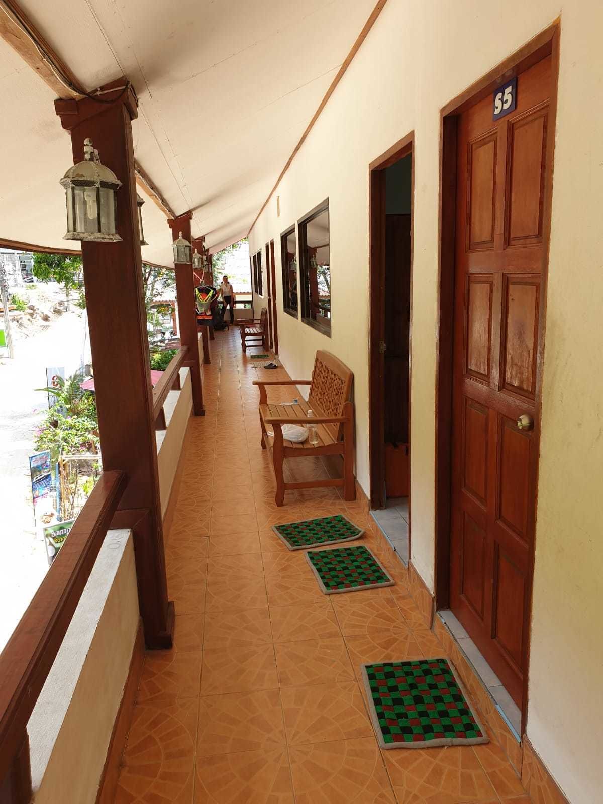 A corridor with wooden benches, a door marked '55', and a tiled floor.