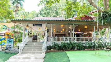 A restaurant with a covered outdoor seating area, steps leading up to it, and a sign indicating it is a full moon party taxi service.