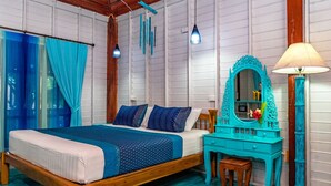 A bedroom with a wooden bed, a turquoise dresser, and a mirror with a lamp. - Baan Kiao Resort (Ko Pha-ngan)