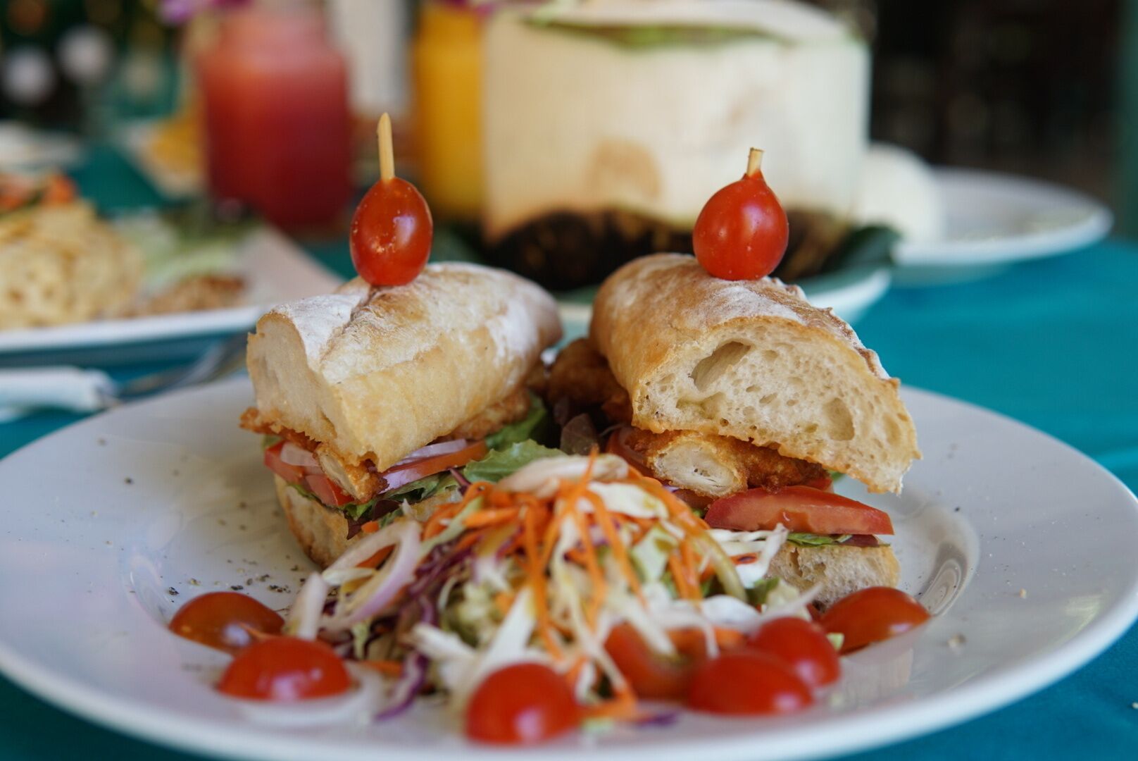 A sandwich with a side salad and cherry tomatoes on a plate.