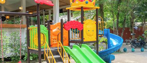 Ein Spielplatz mit Rutsche, Klettergerüsten und einer Zierkrone.