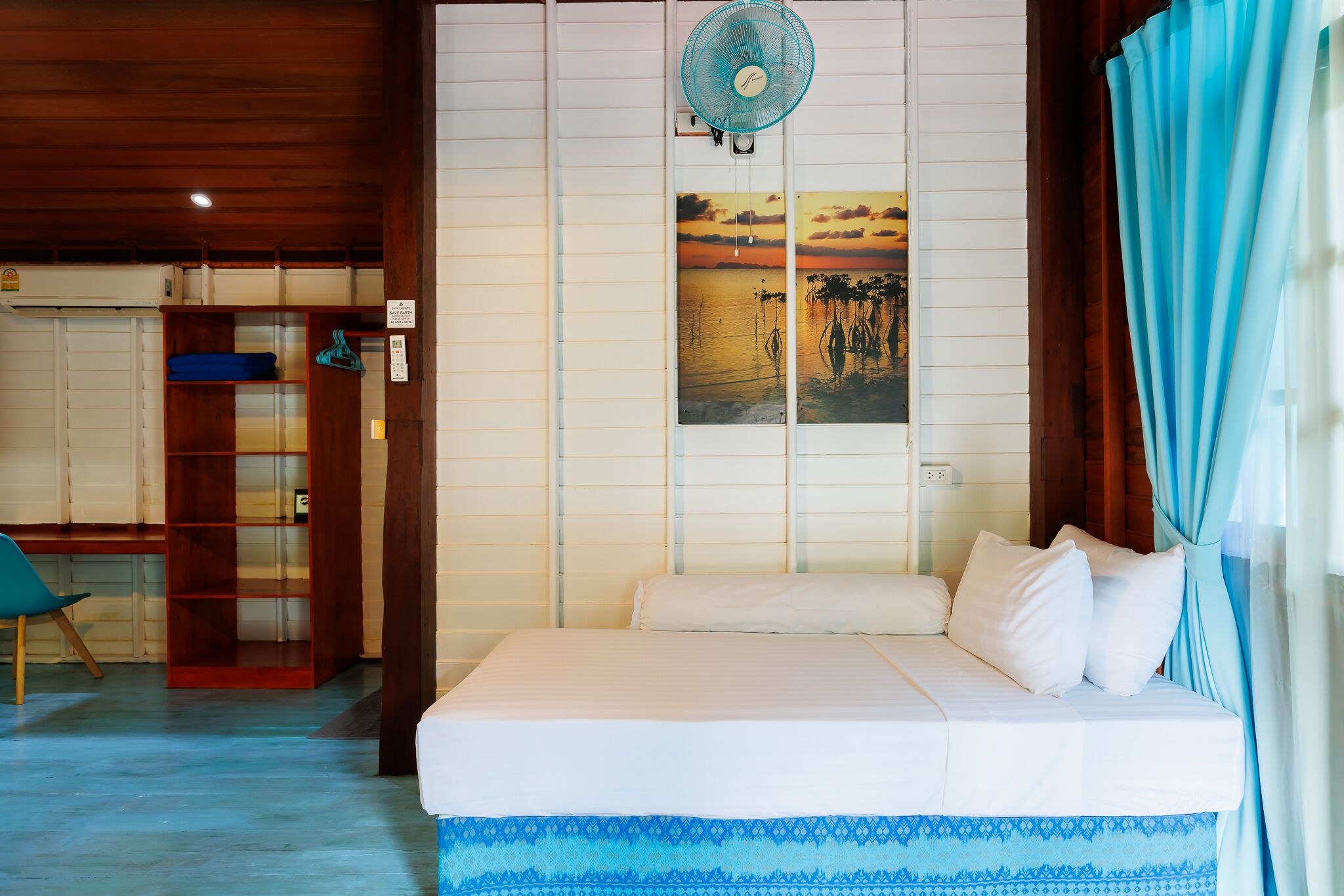 A bedroom with a bed, a wooden wardrobe, a desk, and a chair.