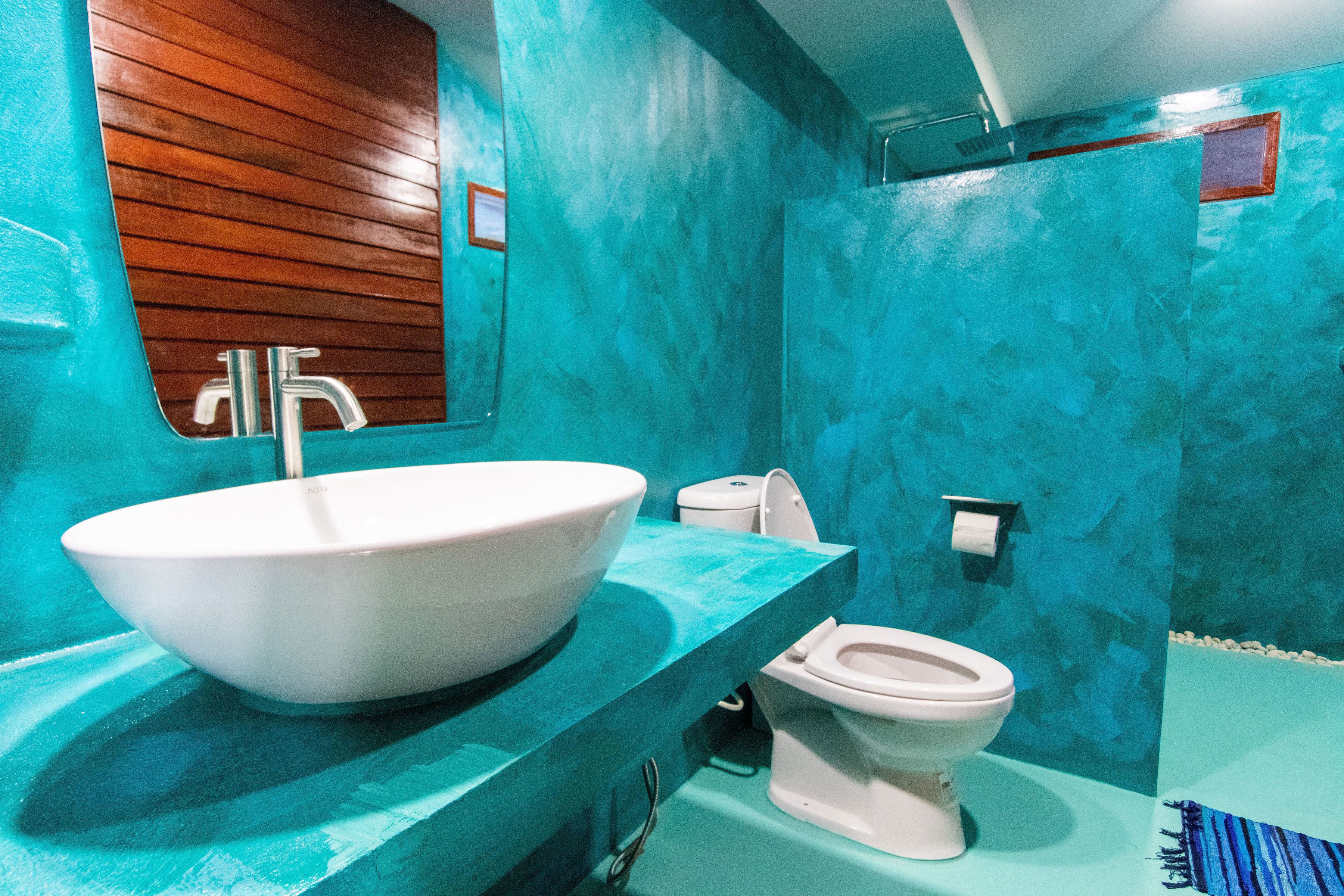 Un bagno con un lavandino ampio e bianco, un water e uno specchio con pannelli in legno.