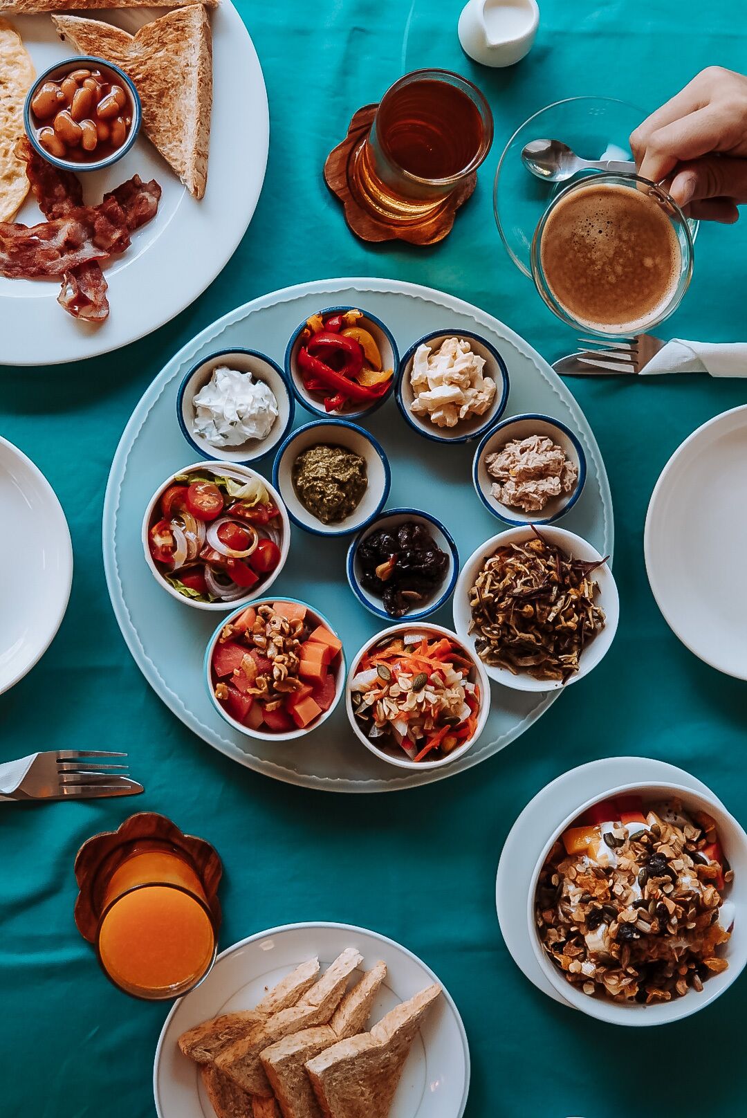 A breakfast setting with various dishes on plates, including toast, beans, and a cup of tea.