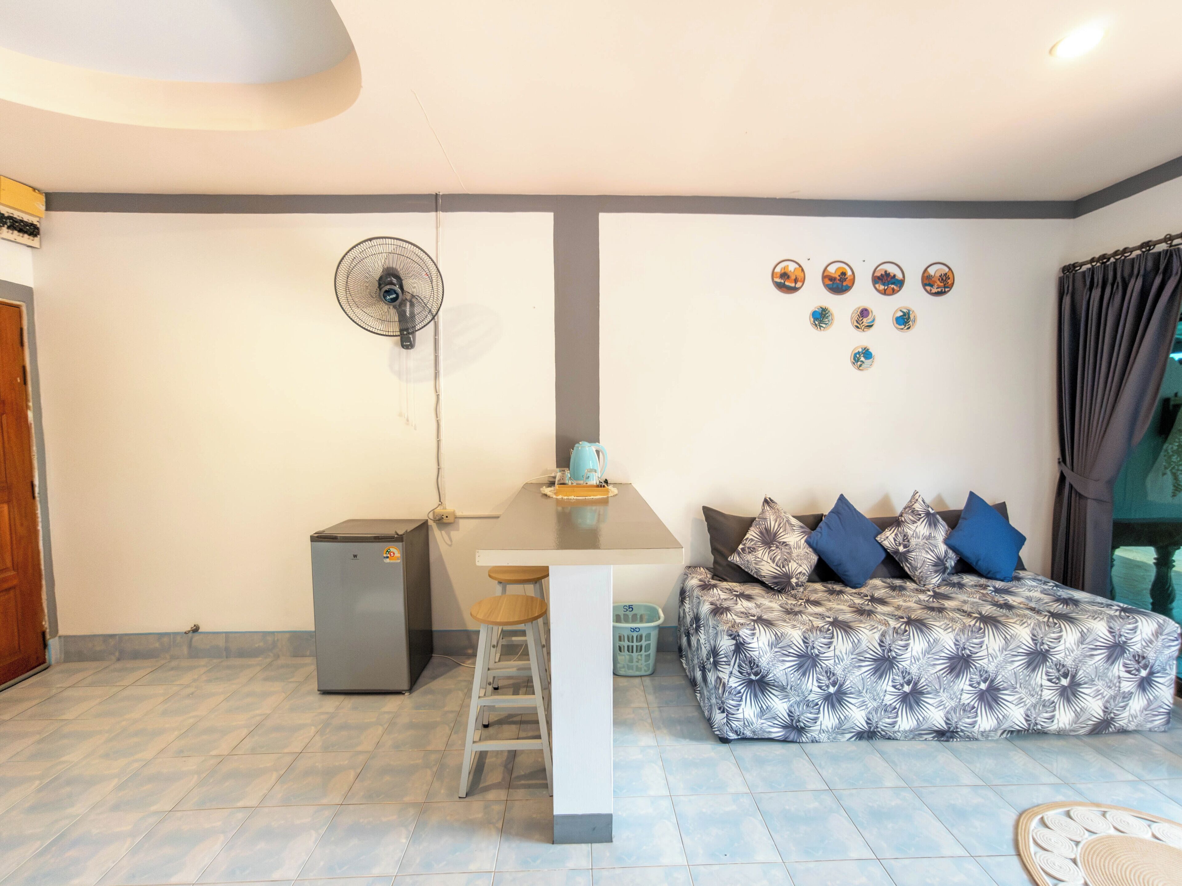 Un espace de vie compact comprenant un coin cuisine, un coin repas et un canapé agrémenté de coussins à motifs.