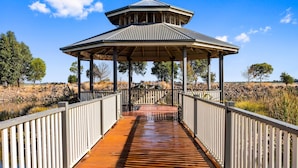 A wooden bridge leading to a gazebo with a peaked roof, surrounded by natural landscape. - Quality Hotel Point Cook (Point Cook)