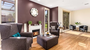 A modern living room with a fireplace, dark-colored furniture, and large windows. - Quality Hotel Point Cook (Point Cook)