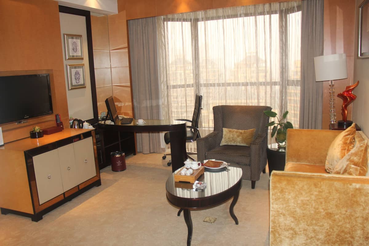 Uma sala de estar com sofá, poltrona, mesa de centro, televisão e um espaço de jantar com mesa e cadeiras.