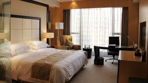 Una habitación de hotel con una cama grande, un escritorio, una silla y un televisor.