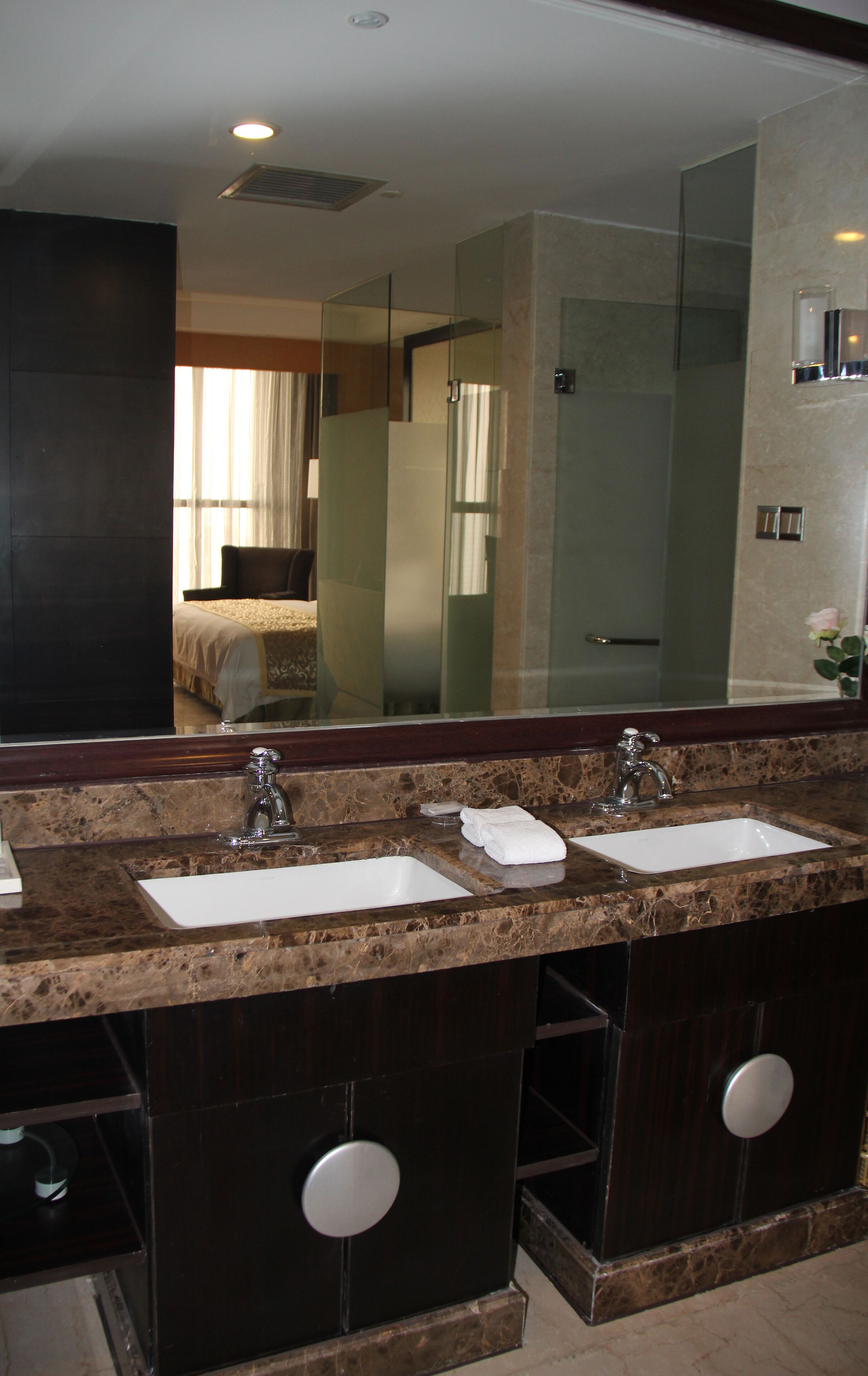 A bathroom with a large mirror, two sinks, and a shower area.