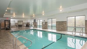 Piscina interior con carriles claramente delimitados, una silla de salvavidas y una zona de estar con mesas y sillas.