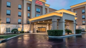 Un Hampton Inn & Suites con fachada de piedra, un acceso cubierto y exterior bien iluminado.