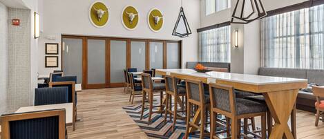 A modern dining area with a long table, multiple chairs, and a patterned rug.