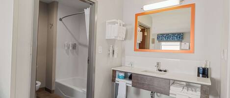 Une salle de bain moderne avec une baignoire, un lavabo avec un miroir et des toilettes.