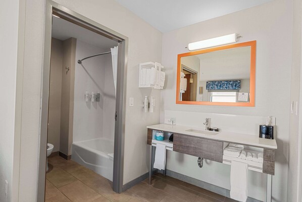 Une salle de bain moderne avec une baignoire, un lavabo avec un miroir et des toilettes.
