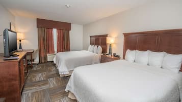 A hotel room with two beds, a desk with a television, and a carpeted floor.