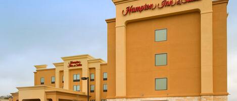 A Hampton Inn & Suites building with a beige facade and stone accents.