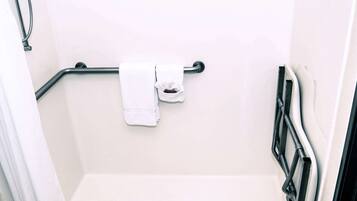 A bathroom with a shower, a grab bar, and a towel rack.