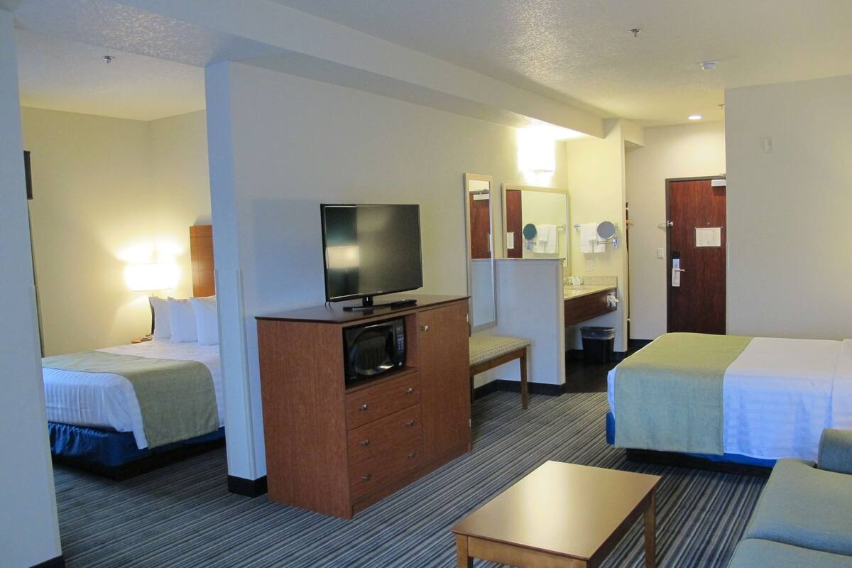 A hotel room with two beds, a TV, a desk, and a bathroom.