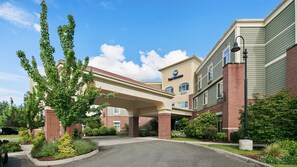 A hotel with a covered entrance, brick facade, and landscaped surroundings. - Best Western Liberty Inn DuPont JBLM (Dupont)