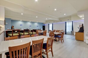 A spacious dining area with multiple tables and chairs, a reception desk, and a blue wall with signage. - Best Western Liberty Inn DuPont JBLM (Dupont)