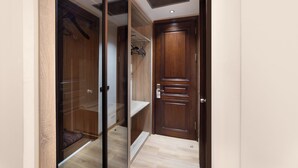 A walk-in closet with a wooden door, a mirrored closet door, and a shelf with hangers. - Atik Palace Hotel (Istanbul)