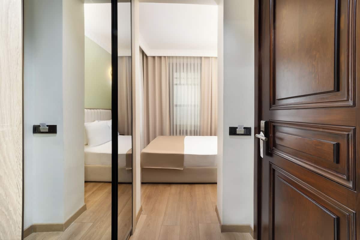 A hotel room with a bed, a bedside table, and a wooden door.