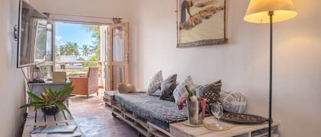 A cozy room with a bed made of wooden pallets, a TV, a lamp, and a painting on the wall.