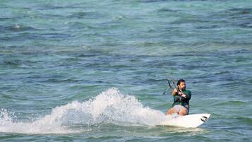 A person windsurfing on a white surfboard in the ocean.
