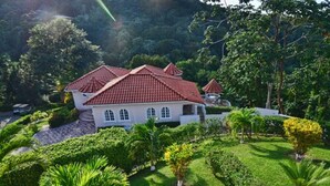 A large, white building with a red roof, surrounded by well-maintained gardens and trees. - Tropical Lagoon Resort (Port Antonio)