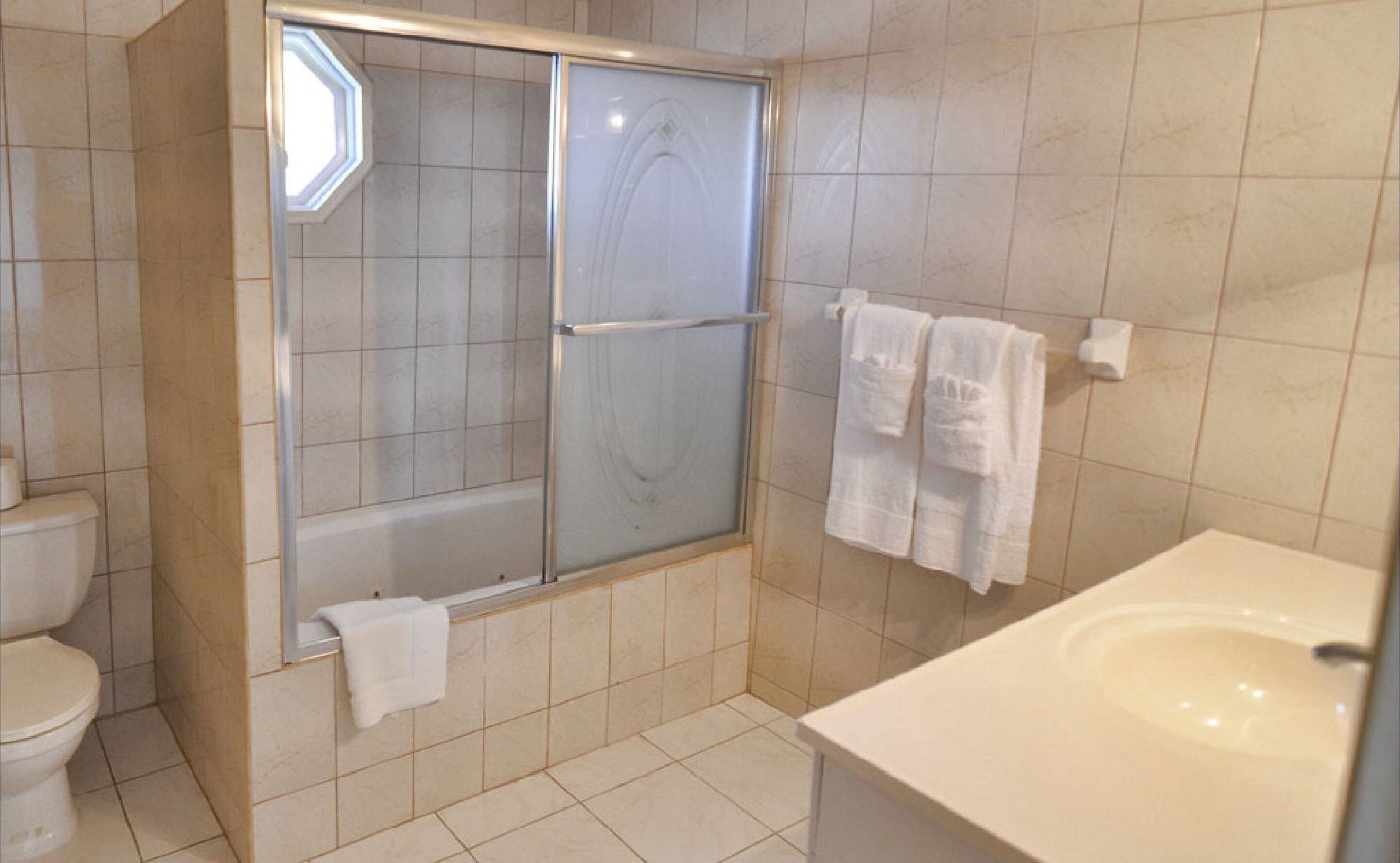Un baño con ducha de vidrio, inodoro y lavamanos con espejo.