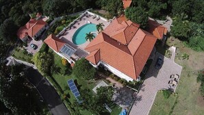 An aerial view of a property with a swimming pool, a tennis court, and a large garden area. - Tropical Lagoon Resort (Port Antonio)