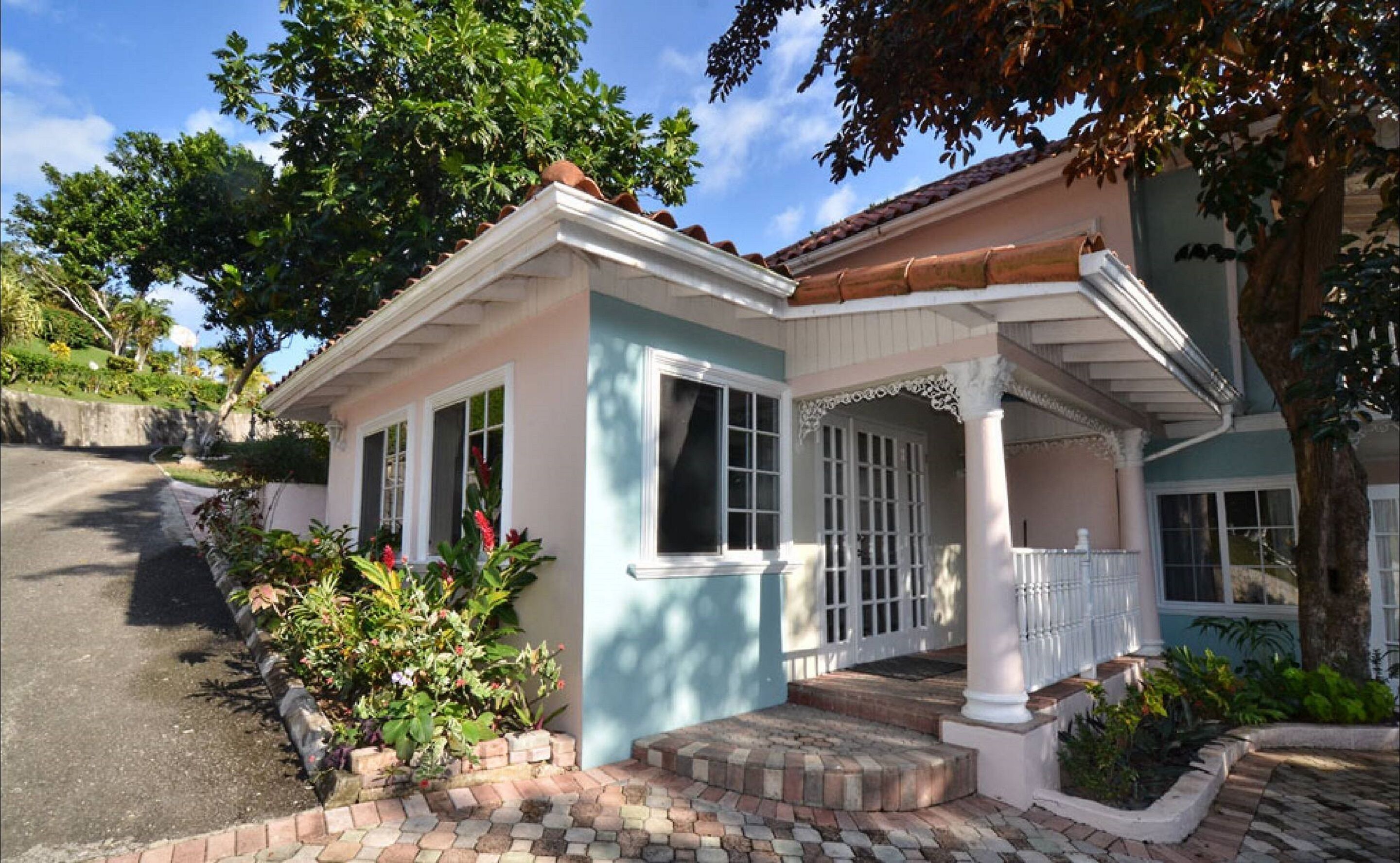 A two-story house with a porch, a driveway, and a garden.