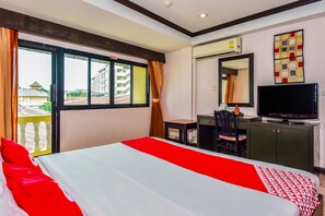 Habitación de hotel con una cama, un escritorio, una silla, un televisor y un ventanal grande.