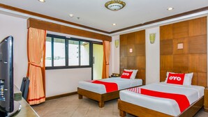 Habitación de hotel con dos camas, cabeceros de madera, un escritorio con computadora y una ventana con cortinas.