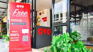 Entrada de hotel con un gran letrero rojo que anuncia un cupón de descuento del 100% para la aplicación OYO.
