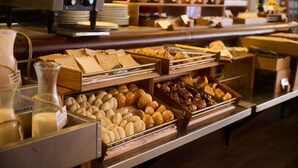 Un bufé con diversas opciones de comida, incluyendo pan, pastelería y una máquina de café.