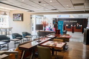 A hotel lobby with a reception desk, seating area, and a large vase with red flowers.