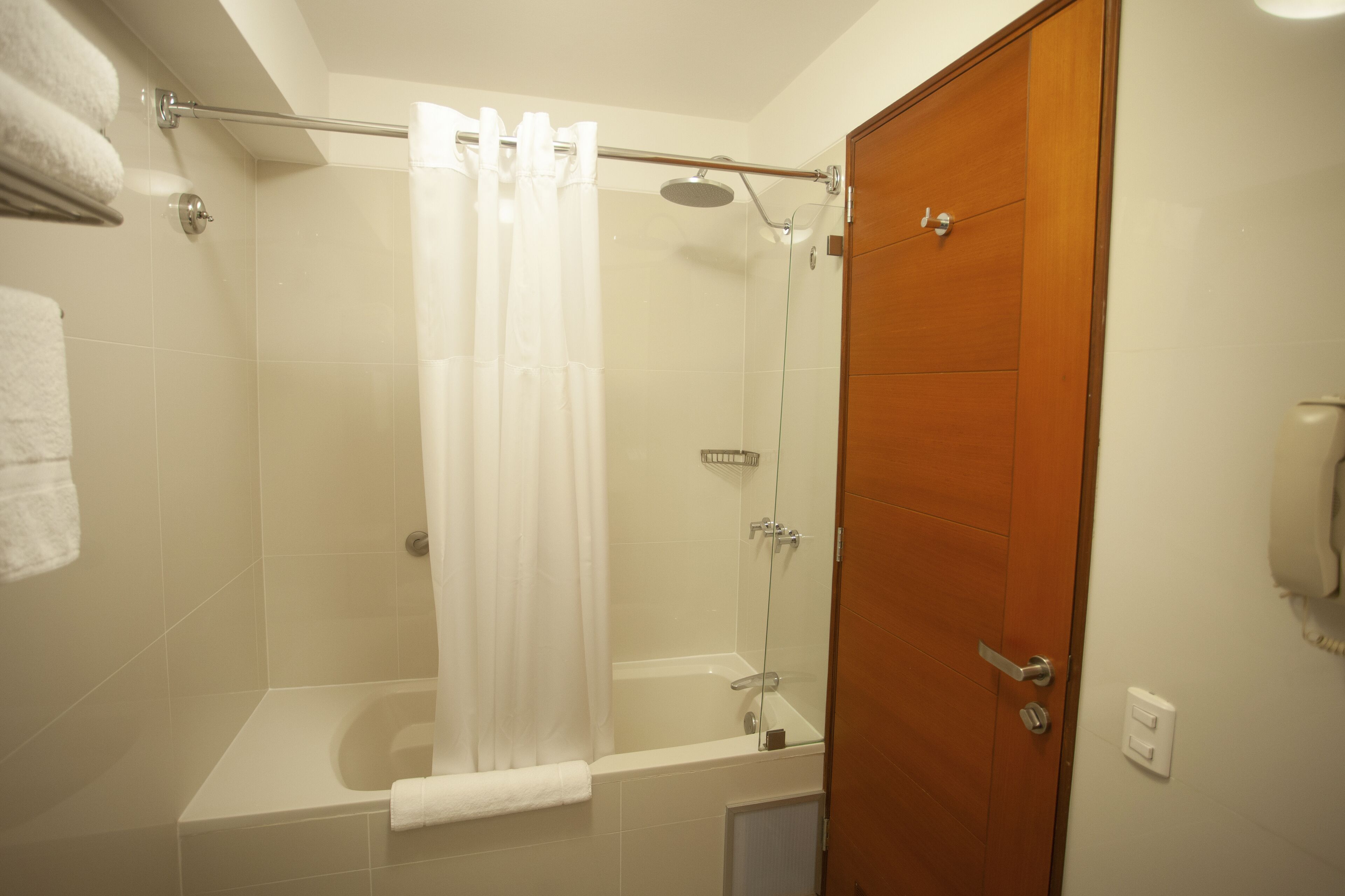 Ein Badezimmer mit Dusche, Badewanne und Holztür.