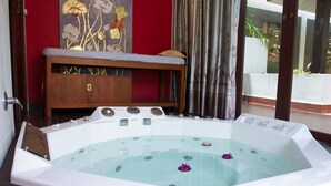 A spa room with a large bathtub, a wooden bench, and a decorative wall. - Tropical Beach Resort Rayong (RAYONG)