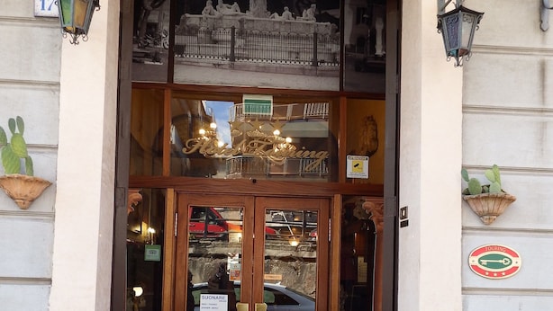 A hotel entrance with a wooden double door, a glass window above, and a sign reading "Hotel". - Hotel Touring (Messina)