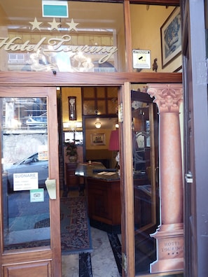 Ein Hotel Eingang mit einer Rezeption, einer großen Säule und einem Schild mit der Aufschrift 'Hotel Touring'.