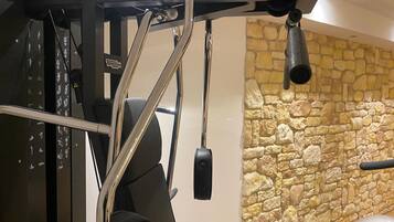 Une salle de sport avec un mur en pierre et du matériel d'exercice.