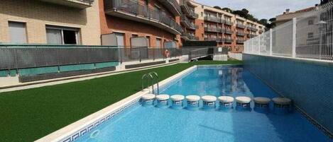 Een buitenzwembad, ligstoelen bij het zwembad