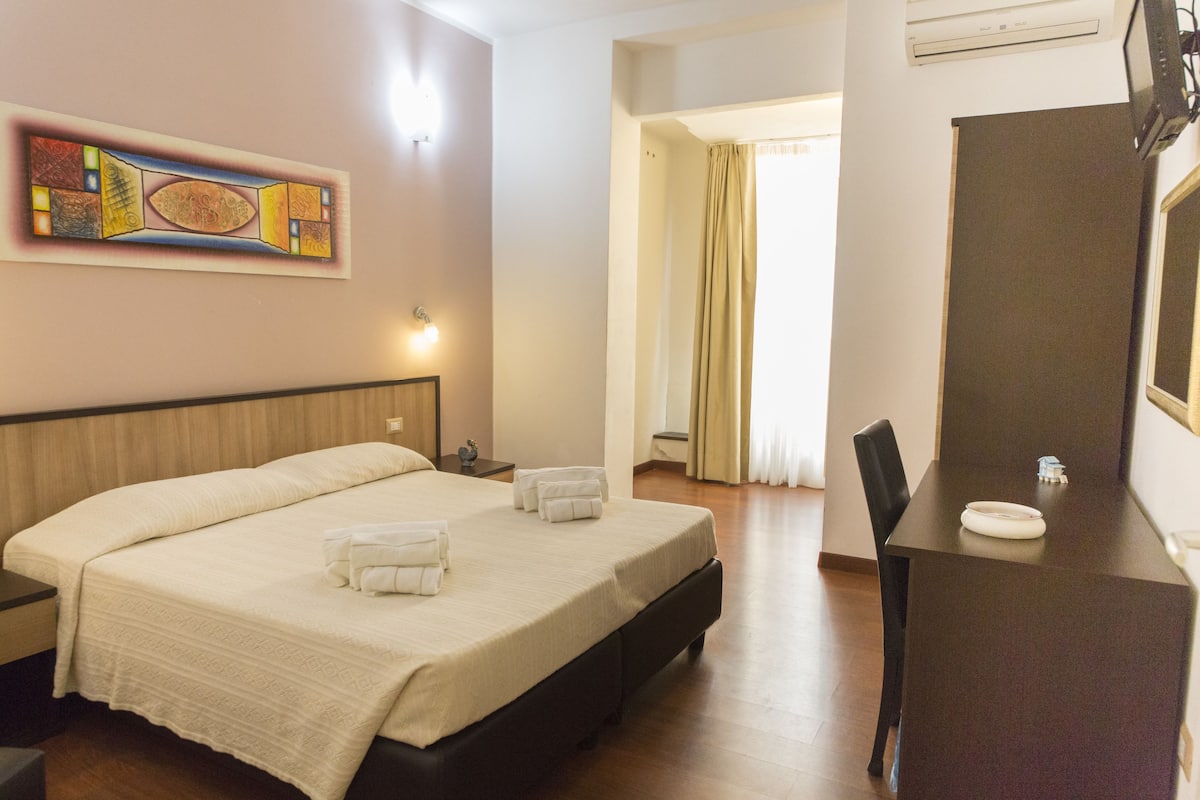 Ein Hotelzimmer mit einem großen Bett, einem Schreibtisch und einem Spiegel.
