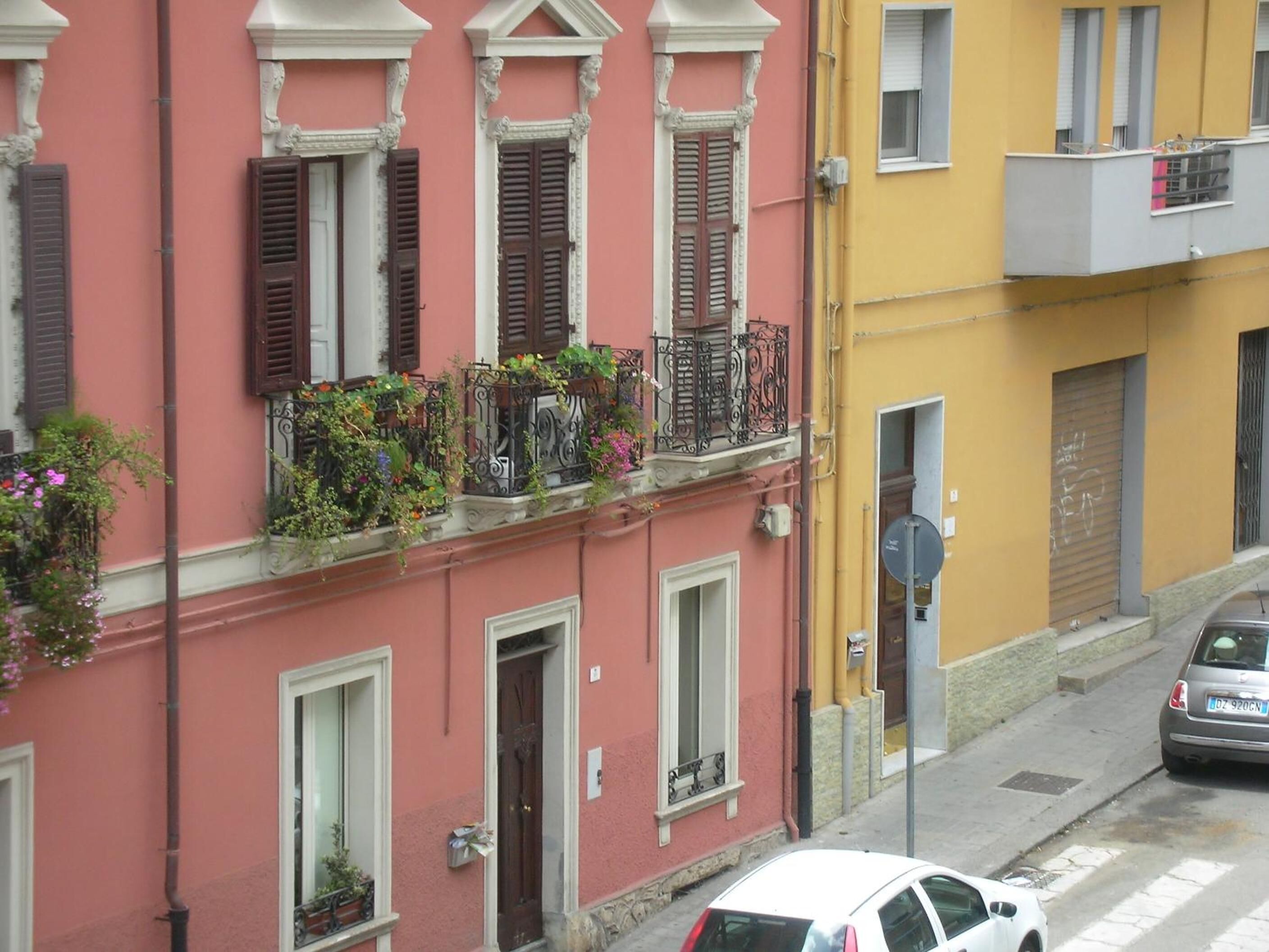 A row of buildings with balconies, some with plants.