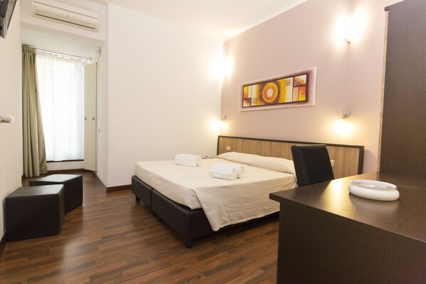 Una habitación de hotel con cama, mesita de noche y un cuadro en la pared.